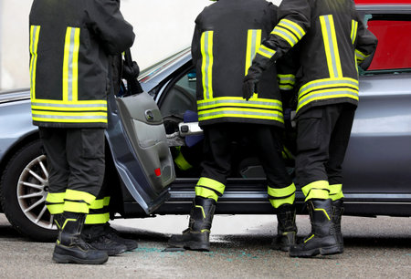 Fire brigade removing the car door to free the injured person after the road accident