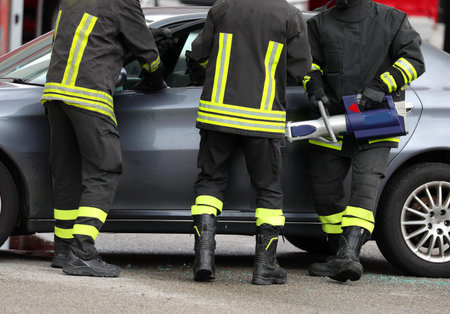 firefighters use a powerful hydraulic retractor called jaws OF LIFE to open the car door after the...