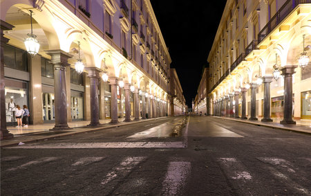 Night view of the road called VIA ROMA in Turin City in Northern Italy with many arcades and large shop windowsの写真素材