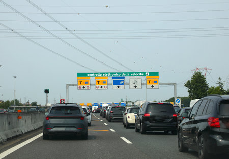 many cars in the italian motorway and gate with text that means electronic speed controlの写真素材