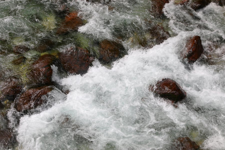 sparkling stream water gushing out of the rocks and rocks in the mountainsの写真素材