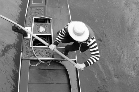 Gondolier with hat while rowing the gondola the typical boat of Venice Island in Northern Italy in black and white effectの写真素材