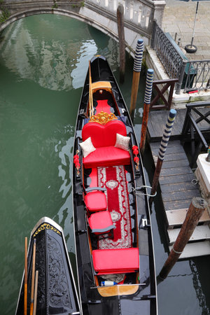 gondola boat deluxe with red seats in the navigable canal in Venice Island in Northern Italy without peopleの写真素材