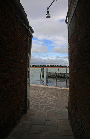 Adriatic Sea and the Cemetery Of Venice Island between two walls of buildings and the street called FONDAMENTA NUOVE in Northern Italyの写真素材