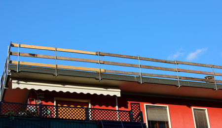detail of barrier with wooden planks firmly installed on the roof for the protection of workers against falling during the repair work of the condominium without peopleの写真素材