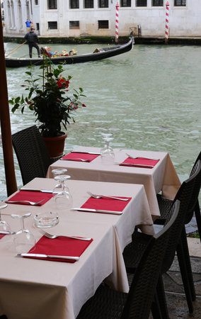 set table of the outdoor restaurant on the banks of the Grand Canal in Venice and the Rialto Bridge in the backgroundの写真素材