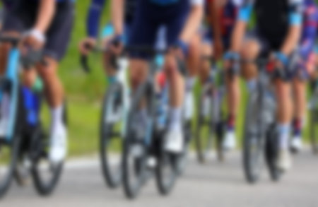 Intentionally blurred group of cyclists energetically pedaling their racing bikes during competitive road raceの写真素材