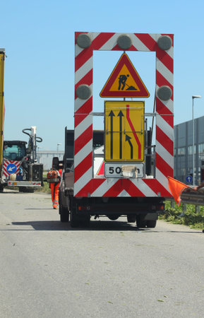 road maintenance truck with large road signs and the narrow lane symbol to warn motorists