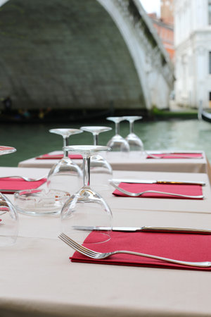 set table of the outdoor restaurant on the banks of the Grand Canal in Venice in ITALY and the Rialto Bridge in the backgroundの写真素材