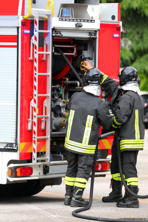 firefighters with uniforms and protective helmets and fire trucks in action during emergency in the...