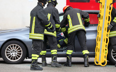 firefighter team frees injured person from twisted car wreckage after road accident and yellow...