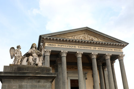 historic neoclassical building with large columns and statues under a cloudy sky in an urban setting...
