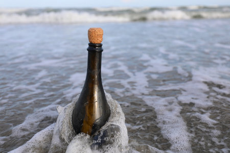 Green glass bottle with a cork stopper containing a secret message or a treasure map by the seaの写真素材
