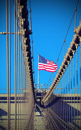 waving american flag above the pillars of the brooklyn bridge a symbol of new york city with old...
