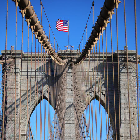 American Flag on the top of Brooklyn Bridge and many steel cables in New York City in USA