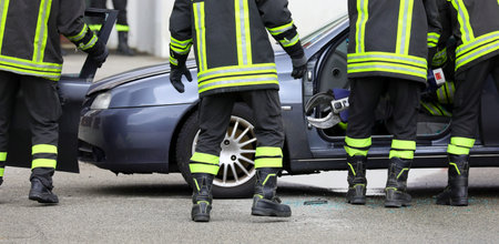 group of firefighters cutting the metal of the crashed car to free the injured person after the road...