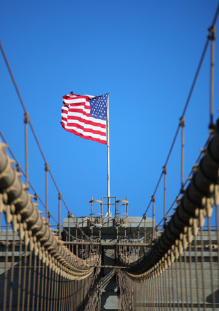 large waving american flag above the Brooklyn Bridge iconic image of New York and all of Americaの写真素材