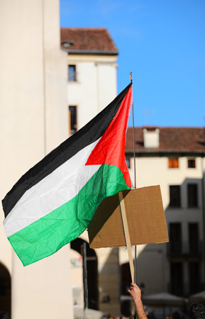 Palestinian flag waved by protester holding a sign during city protest against war