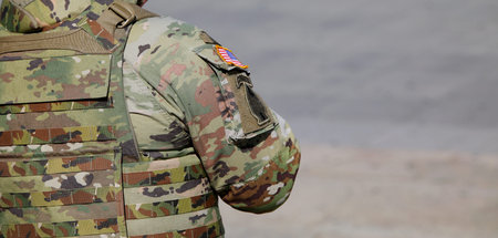 American army soldier on patrol with a camouflage uniform and a flag on the sleeve