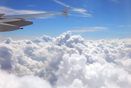 Many soft white clouds and the wing of an intercontinental plane flying over 40000 feet
