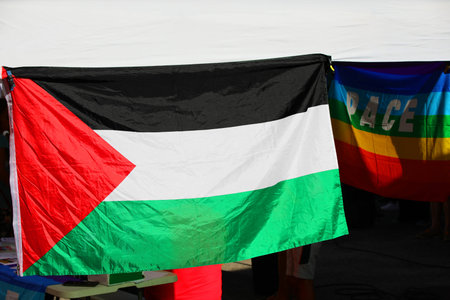 white gazebo during a demonstration with Palestine Flag and the colorful flag with text PACE that...