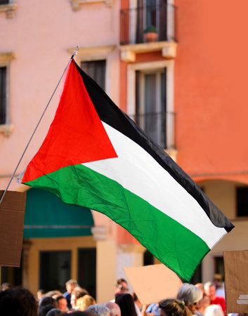 waving flag of Palestine during a peaceful protest demonstration with people holding placards
