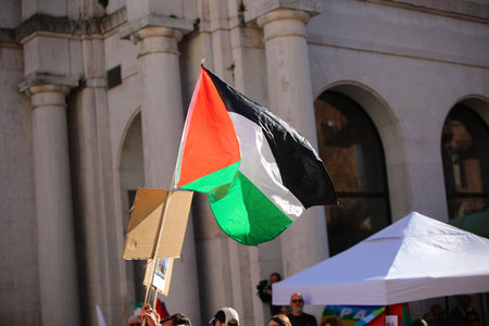 Protest demonstration featuring large waving Palestine flag in European city squareの写真素材