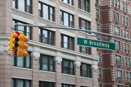 new york street intersection with the w broadway street sign and the large red traffic light above with buildings in the backgroundの写真素材