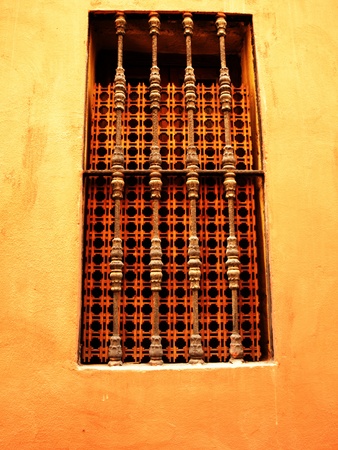Window with a lattice against brightly yellow wall.の写真素材