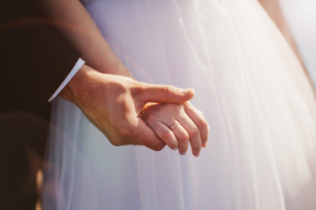 A couple of loving newlyweds holding hands together.の写真素材