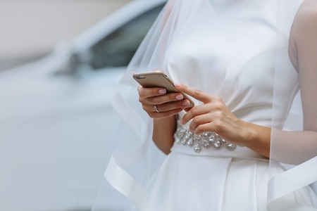 Elegant bride with phone in hands on a white backgroundの写真素材