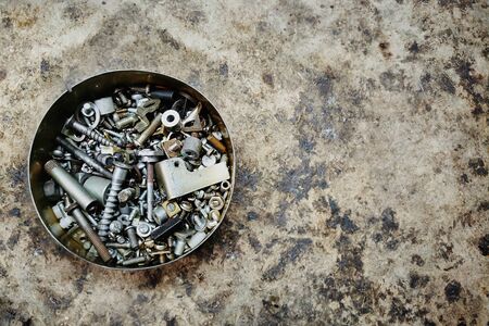 bunch of bolts and screws of various sizes lie in a round metal boxの写真素材
