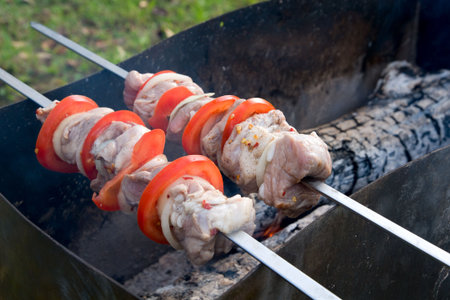 Barbecue cooking - big pieces of marinated pork with tomatos and onionの写真素材