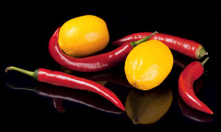 Lemons and peppers isolated on black background with reflectionの写真素材