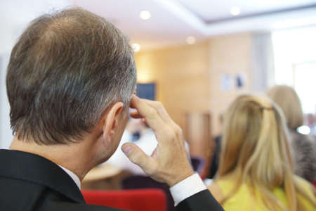 Man listening in conference hall, blurred backgroundの写真素材