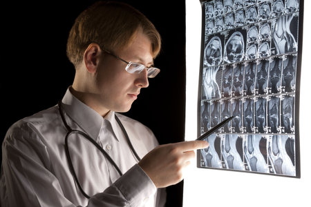 Doctor pointing at the MRI scan in dark room