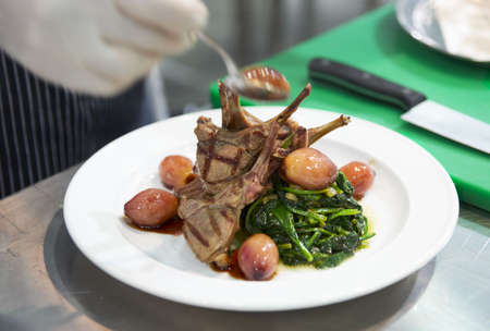 Chef is decorating grilled rack of lamb on restaurant kitchenの写真素材