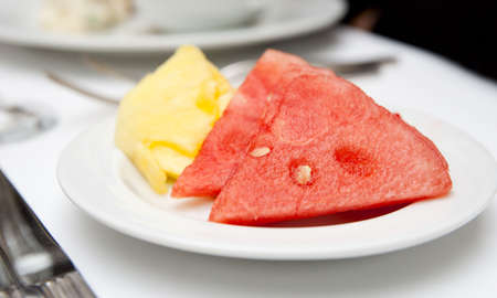 Pieces of watermelon and pineapple on white plate, closeupの写真素材