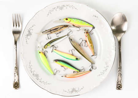 Porcelain plate with plastic fishing lures isolated on white. Artificial food concept or just fishing theme.の写真素材