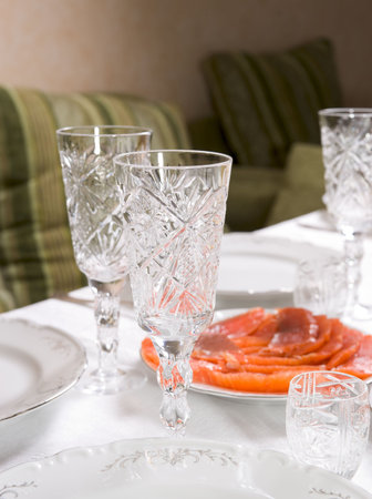 Arranged table - sliced salmon, crystal glasses and porcelain plates