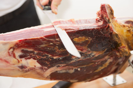 Man slicing jamon (prosciutto), selective focus is on cut piece