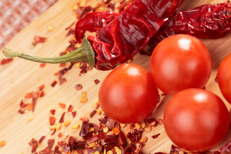 Hot pepper and cherry tomatos on wooden plankの写真素材
