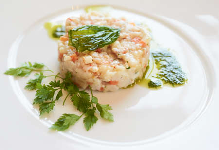 Elegant seabass tartare with parsley and pesto topped with fried basil leafの写真素材