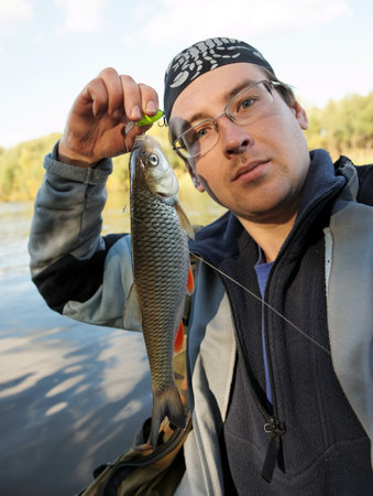 Fisherman holds chub caught on a green hardbait