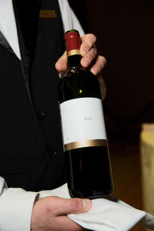 Sommelier displaying wine during formal dinner, TMs removed from the bottleの写真素材