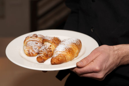 Chef holding plate with fresh baked croissants, copy spaceの写真素材