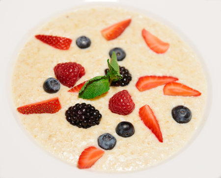 Oatmeal porrige in plate with various berries, close-up