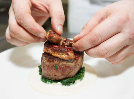 Chef is topping tenderloin steak with fried foie gras piecesの写真素材