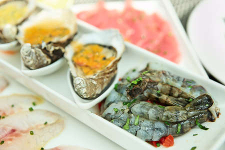 Plate with oysters, seabass, tuna and shrimps on restaurant table の写真素材