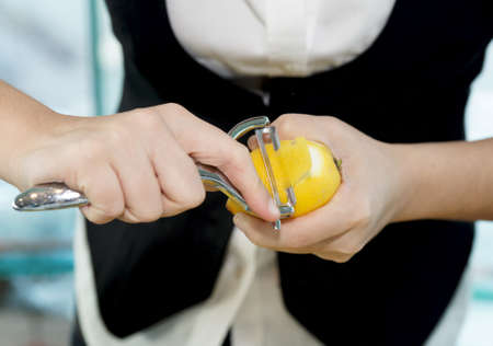 Female bartender peeling lemon to make cocktailの写真素材